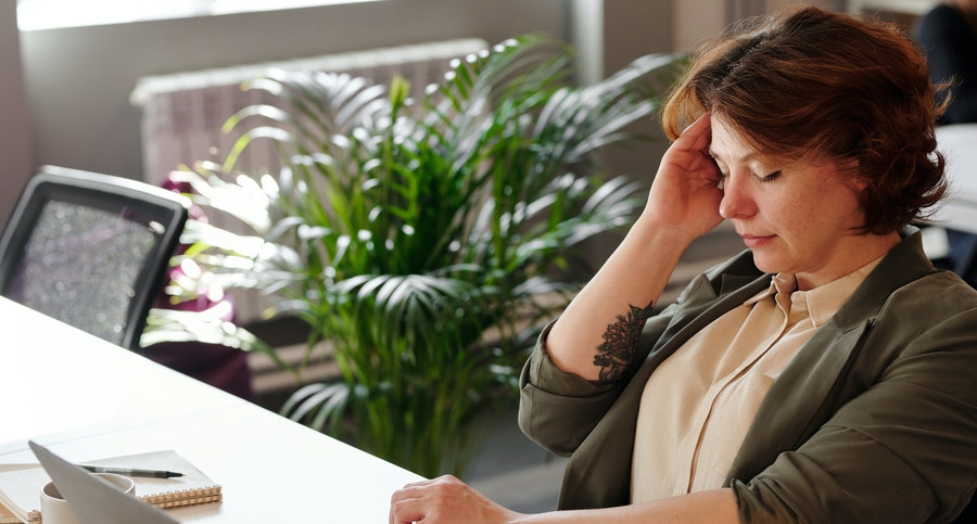 woman holding her head while working from home