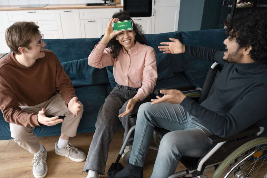 three people playing a game using a mobile phone, sitting on a sofa and wheelchair