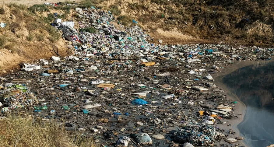 A polluted shoreline filled with plastic waste and debris, highlighting the environmental limits of recycling.