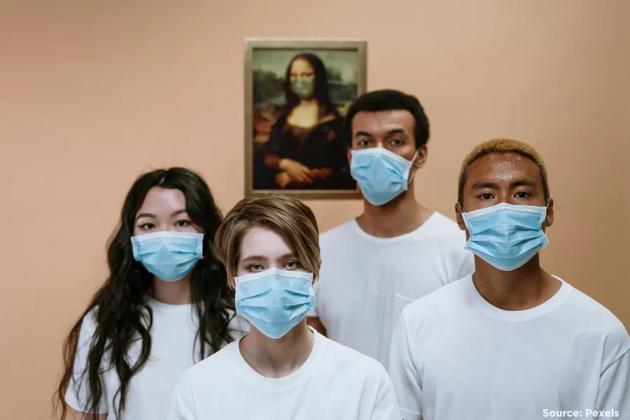 four people wearing masks and looking at the camera