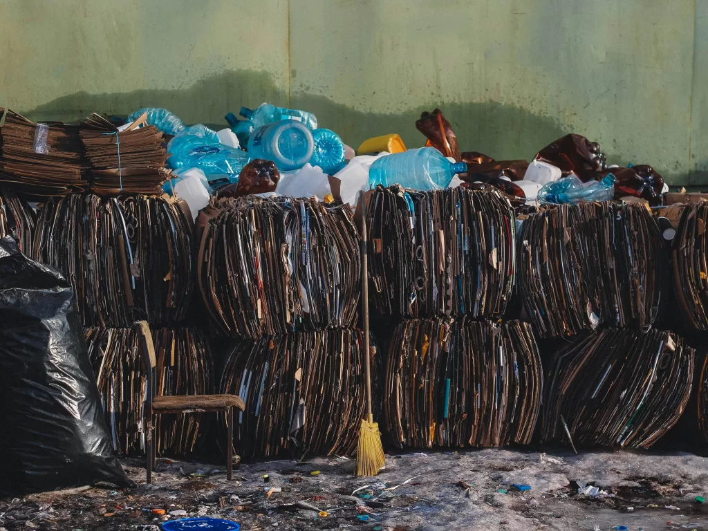 Baled cardboard and discarded plastic bottles at a recycling collection site, reflecting efforts in municipal solid waste separation and material recovery.