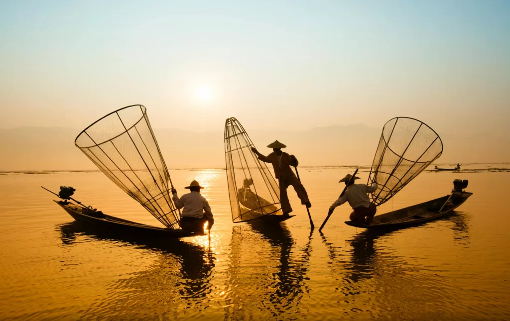 Men are fishing with nets on a boat.