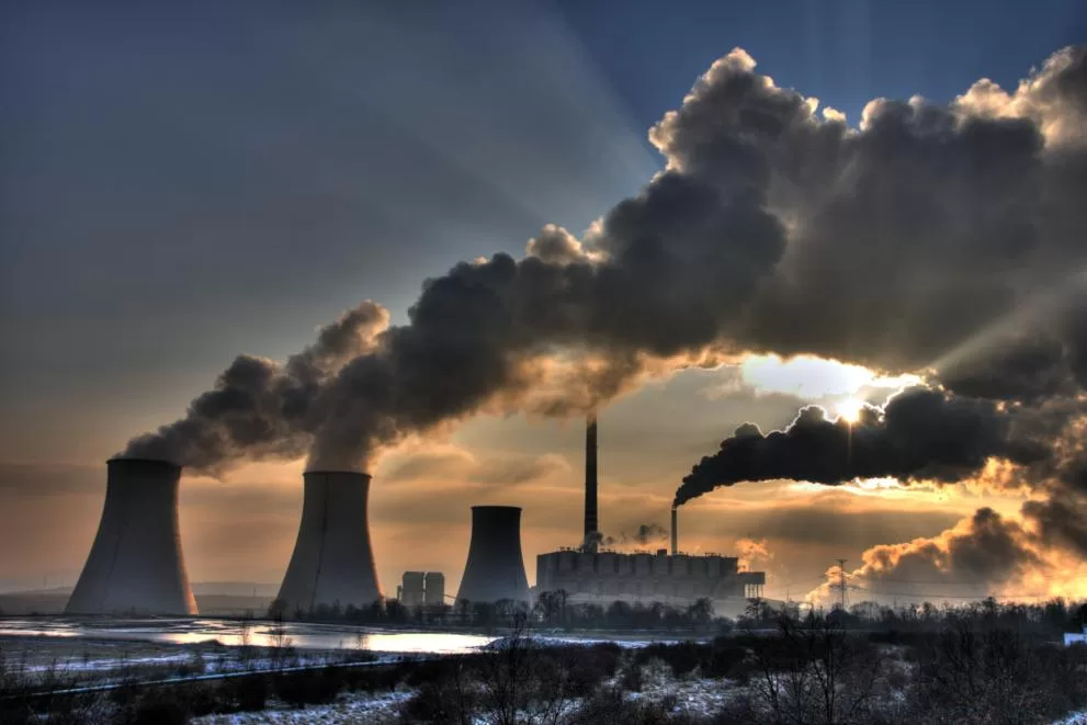 Carbon emissions from smokestacks with sun being obscured.